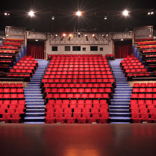 Inside of theatre 1 from the stage with tiers of red seats going up along the back wall
