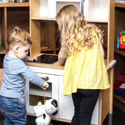 Two children playing with a toy kitchen