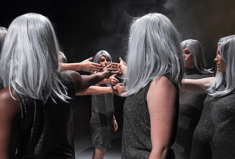 Group of people stood in a circle all wearing the same clothes and hair touching hands