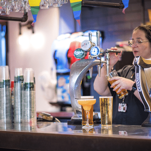 Person working behind the bar pulling a pint